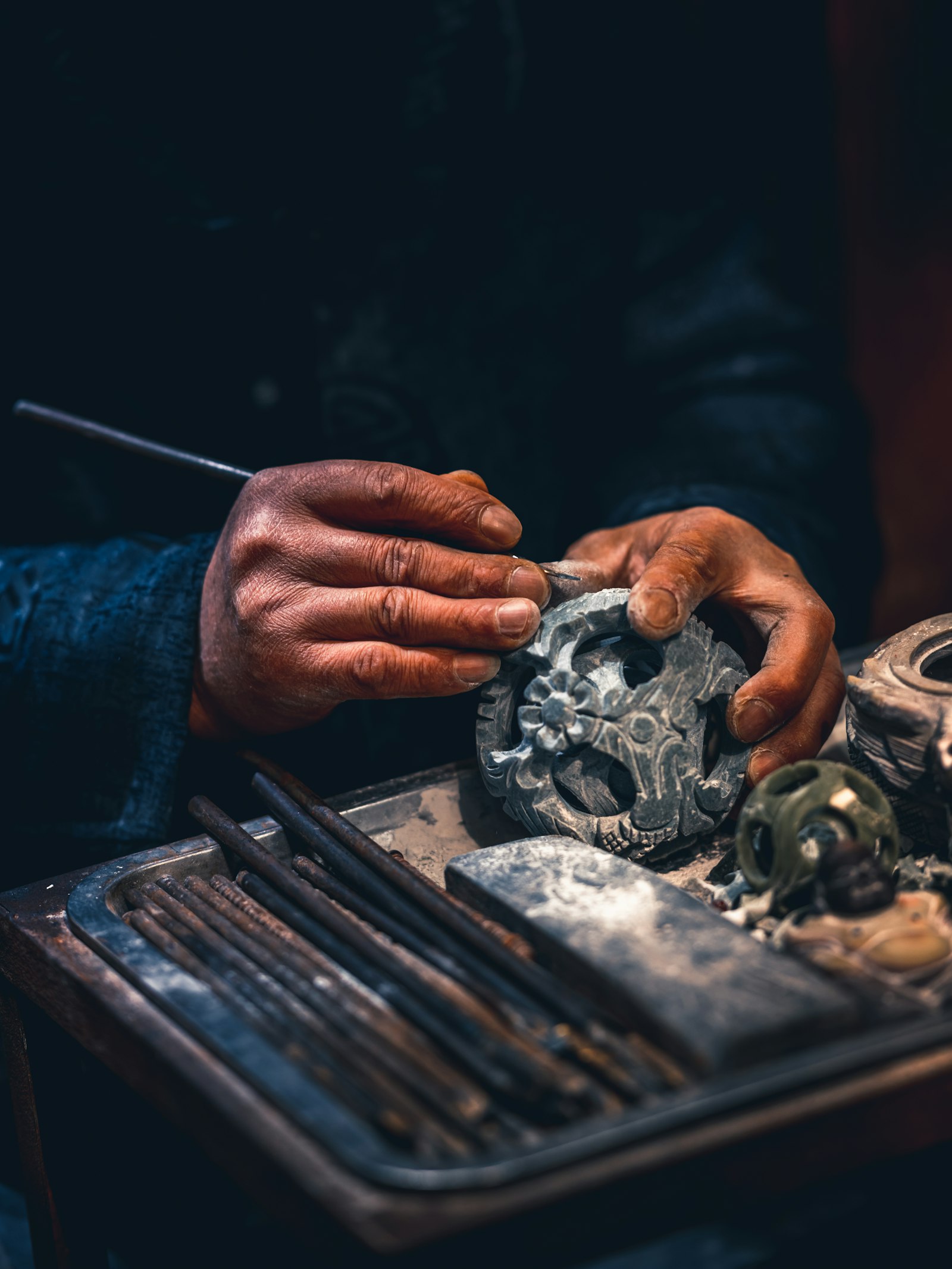 Artisan carves intricate details into stone sculpture.