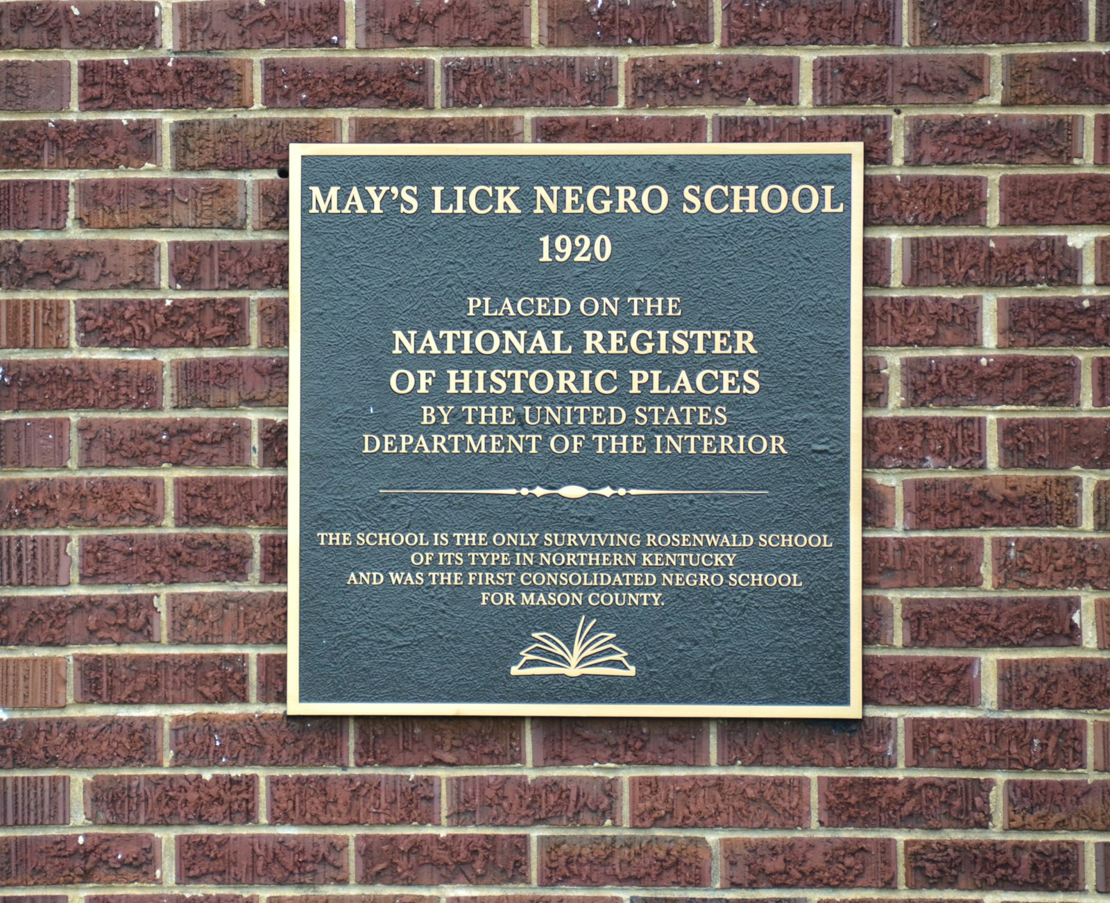 A bronze historical marker for the May's Lick Negro School on a brick wall.