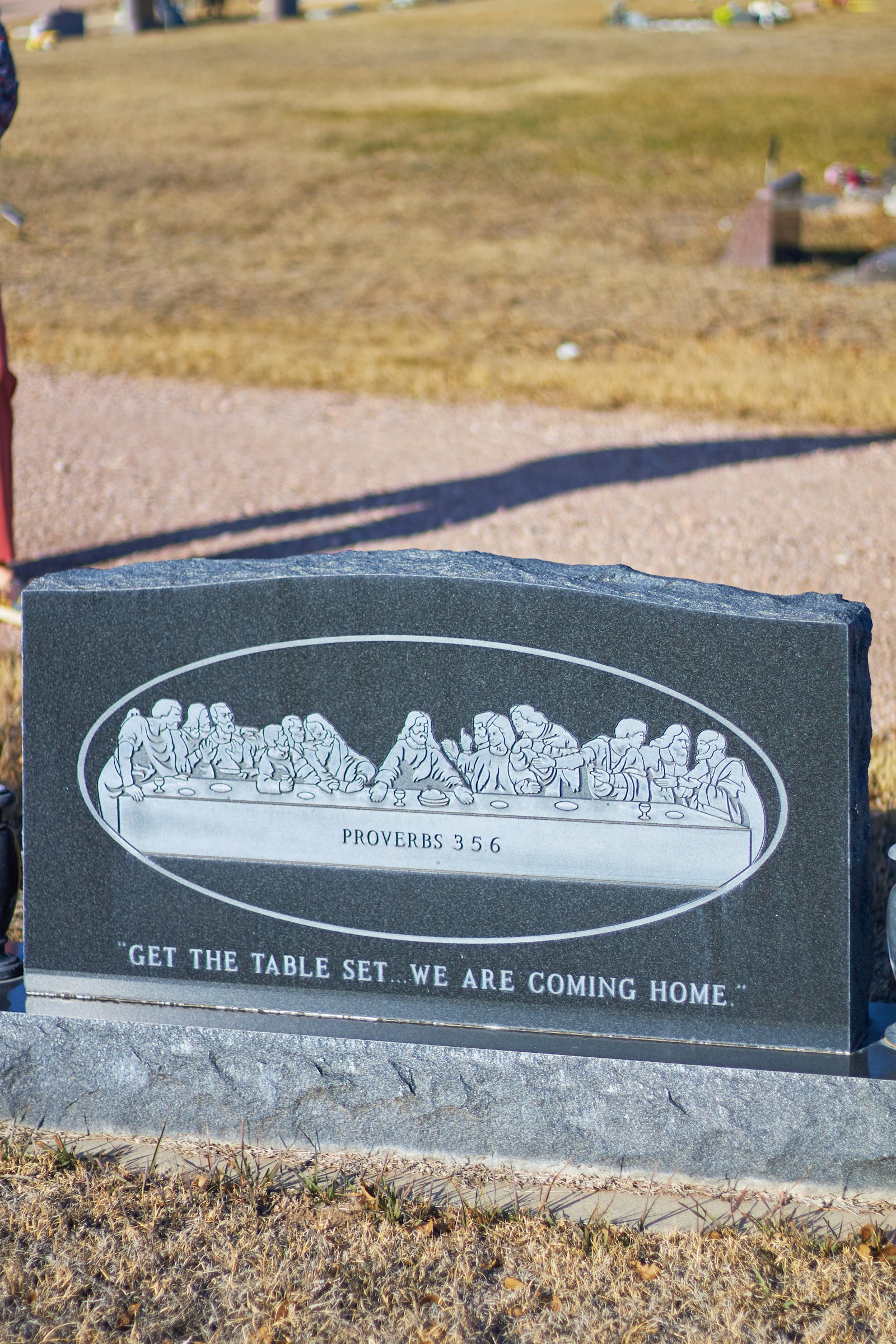 Tombstone with "the last supper" engraving and quote.